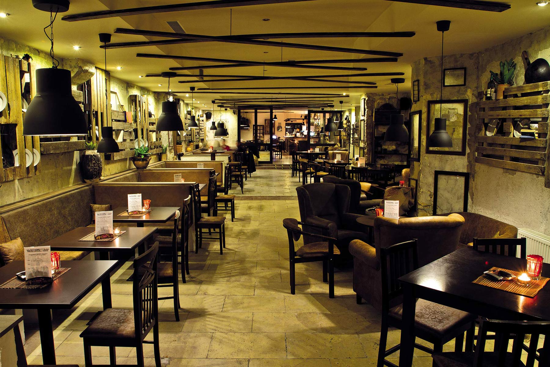 Neupravené steny, drevené palety symbolizujúce zariadenie starého hostinca, ušiaky a rôzna skladba nábytku majú navodiť celkovú historizujúcu atmosféru.