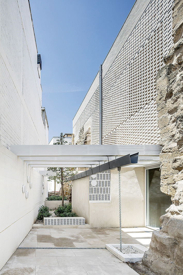 Stavba nového suseda dostala kostol do prieluky. Svojou dvojvrstvovou perforovanou fasádou, ktorá výborne rieši klimatické nároky, je náprotivkom susediaceho mohutného obvodového múru.