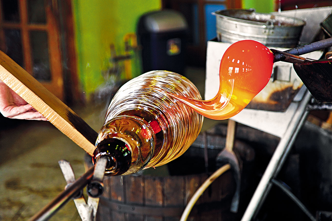 Muži držia v rukách dlhé kovové píšťaly, ktoré sú upevnené v drevených držiakoch, a prikladajú si ich k ústam, aby vyfúkli objem. V strede dielne je mohutná 6-panelová pec so štyrmi otvormi, ktorá pri teplote 1 300 °C tvaruje ich nápady zo skla. Po vytiahnutí z rozpálenej vyhne ich špeciálnymi nožnicami upravujú do žiaduceho tvaru. Sklo vytvára až fantazijné tvary.