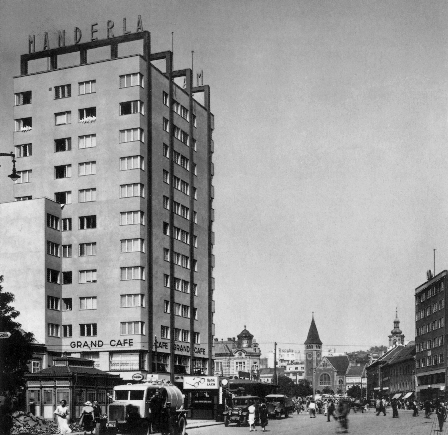 Dobová fotografia obchodného a obytného domu Manderla v Bratislave. Vystrčená hmota objektu sa už počas svojho vzniku stala skutočnou dominantou priestoru a zaslúžene „pupkom“ Bratislavy, čo vtedy mnohí veľmi oceňovali. (Zdroj: Foltyn, Ladislav: Slovenská architektúra a česká avantgarda 1918 – 1939. Vydavateľstvo Spolku architektov Slovenska, Bratislava 1993)