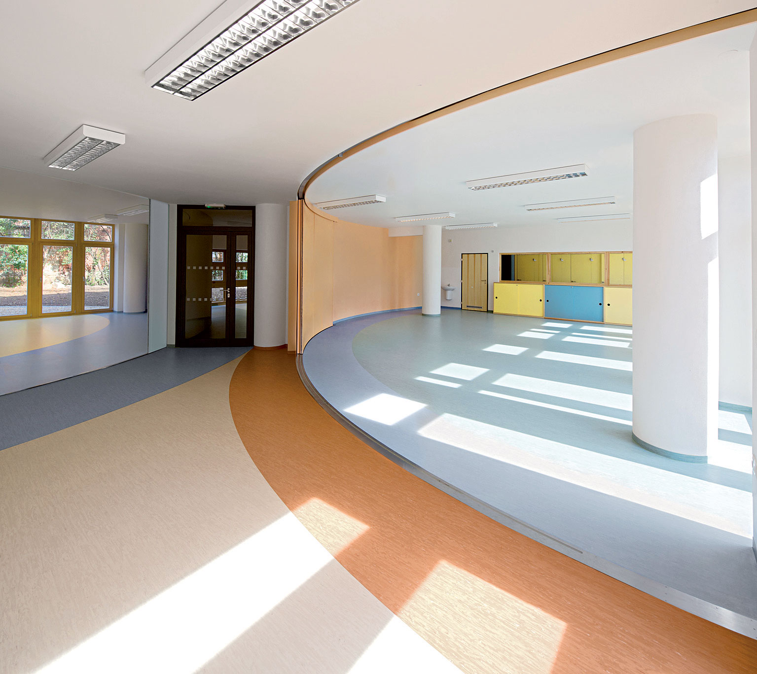 Variabilný priestor materskej školy na prízemí sa dá posuvnými stenami prepojiť. Dnes je plný detí a hračiek.