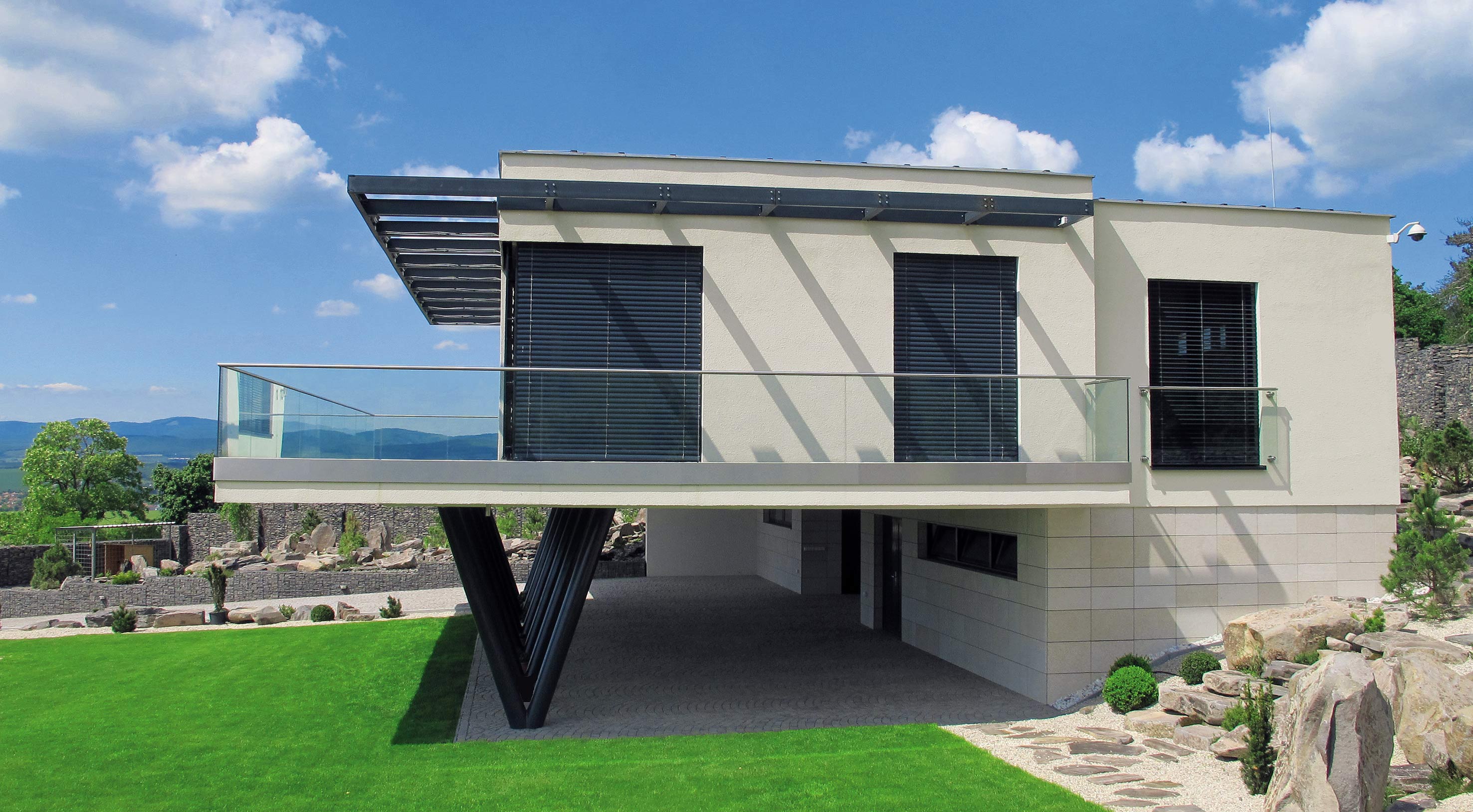 Dve tretiny pôdorysu sú vysunuté do priestoru, čím pod domom vzniká pomerne rozsiahla zastrešená plocha na parkovanie áut.