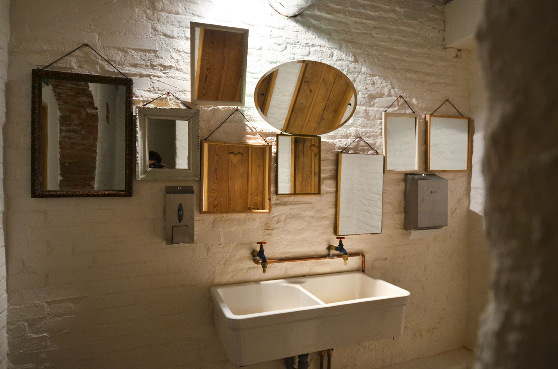 Už pri vstupe vás šokuje množstvo zrkadiel rôznych tvarov a veľkostí, ktoré sú zarámované v mnohorakých rámoch a vytvárajú dramatickú scenériu na bielej tehlovej stene.