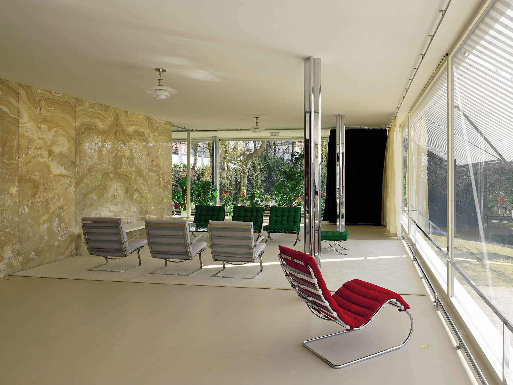 Dve z mohutných okien v hlavnej obývacej časti (delené len posuvnými elementmi závesov a ľahkou ónyxovou či makassarovou priečkou) po stlačení tlačidla s tichým bzučaním zmiznú pod podlahou. Ilúzia spojeného otvoreného priestoru je dokonalá.