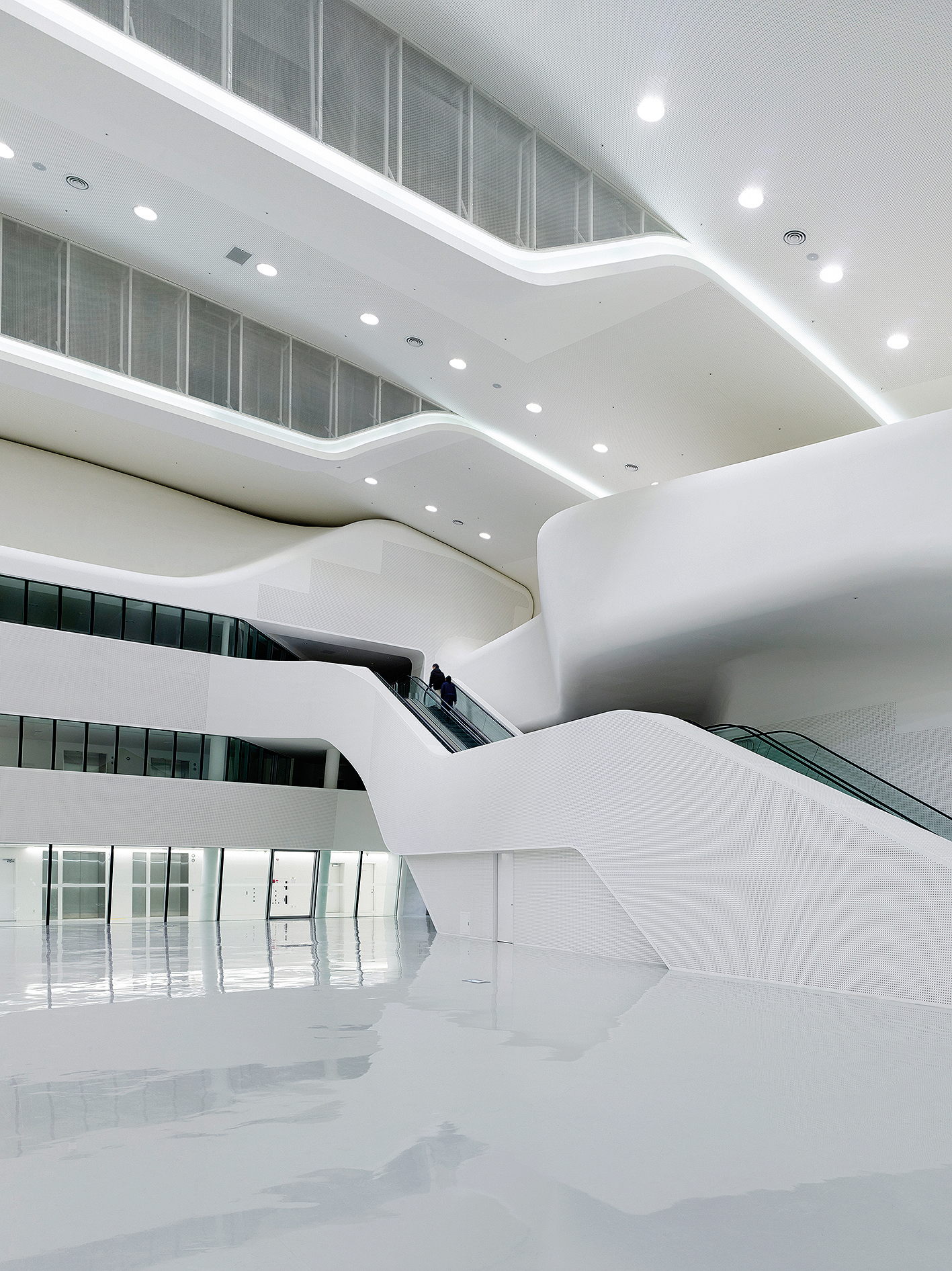 Čitateľnosť amorfnosti je v interiéri podporená čistobielou farebnosťou stien, ktoré takmer plynule prechádzajú do stropov v kombinácii s jednoliatymi sivými epoxidovými podlahami.